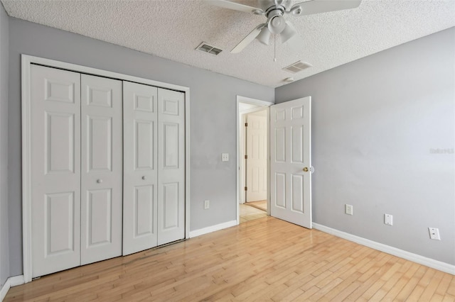 unfurnished bedroom with ceiling fan, light hardwood / wood-style floors, a textured ceiling, and a closet