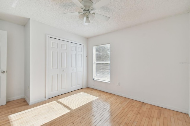 unfurnished bedroom featuring ceiling fan, a closet, a textured ceiling, and light hardwood / wood-style flooring