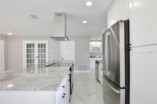 kitchen with wall chimney range hood, appliances with stainless steel finishes, and white cabinets