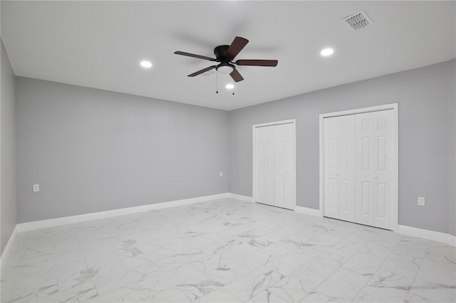 unfurnished bedroom featuring ceiling fan and two closets