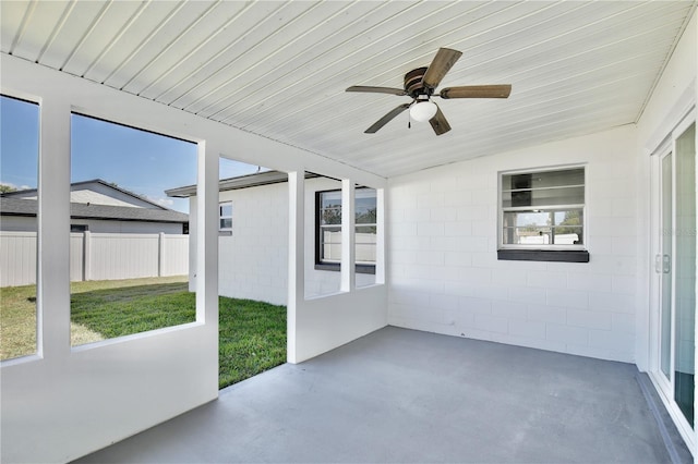 unfurnished sunroom featuring a healthy amount of sunlight, ceiling fan, and vaulted ceiling