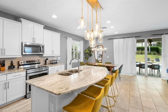 kitchen featuring sink, appliances with stainless steel finishes, white cabinets, and an island with sink