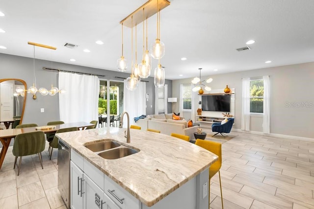 kitchen with a healthy amount of sunlight, sink, an island with sink, and white cabinets