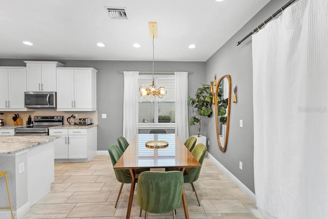 kitchen featuring hanging light fixtures, stainless steel appliances, white cabinets, light stone counters, and a chandelier