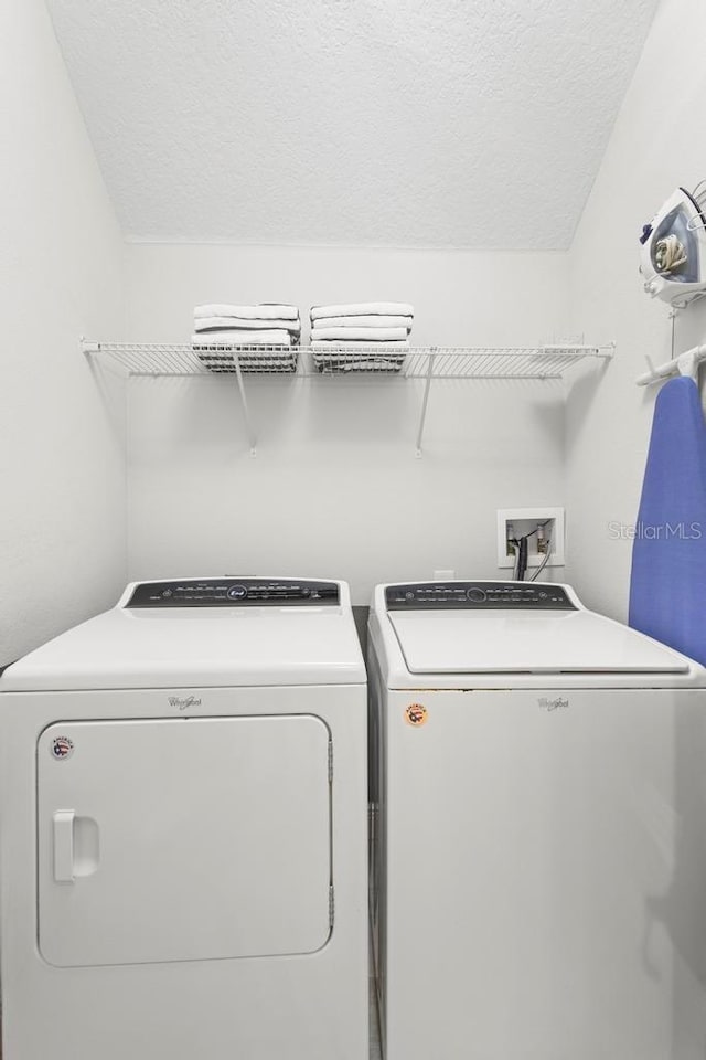 clothes washing area featuring independent washer and dryer and a textured ceiling