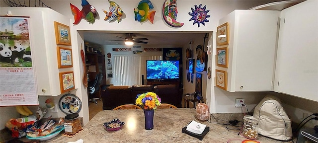 kitchen with white cabinets, ceiling fan, and light stone countertops