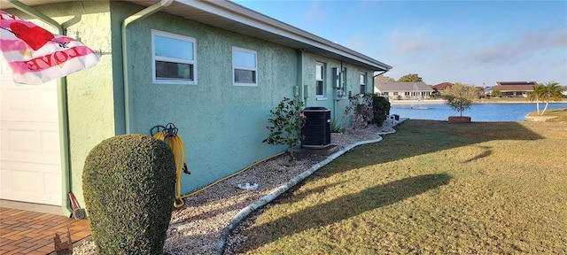 906 Bluewater Dr, Sun City Center, FL 33573 - view of side of home featuring central AC, stucco siding, a lawn, and a water view