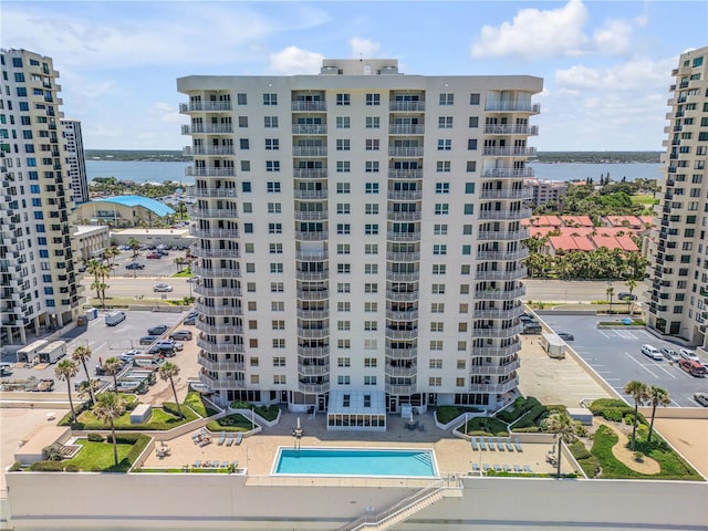 view of building exterior with a community pool and a water view