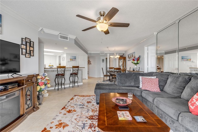 living room with a textured ceiling, light tile patterned floors, ceiling fan with notable chandelier, and ornamental molding