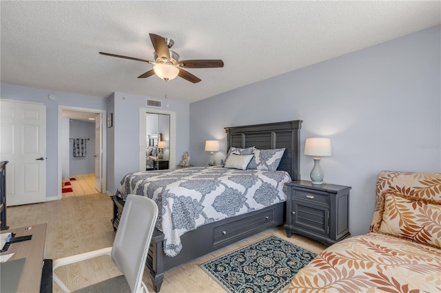 bedroom with ceiling fan, a textured ceiling, and light wood-type flooring