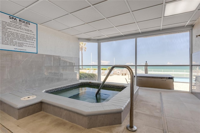 view of swimming pool with an indoor hot tub and a water view