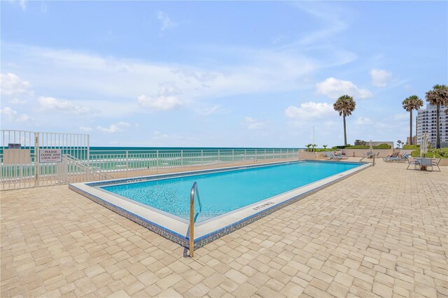 view of pool with a patio and a water view