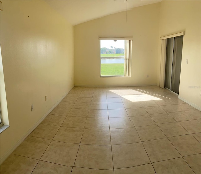 tiled empty room with a water view and vaulted ceiling