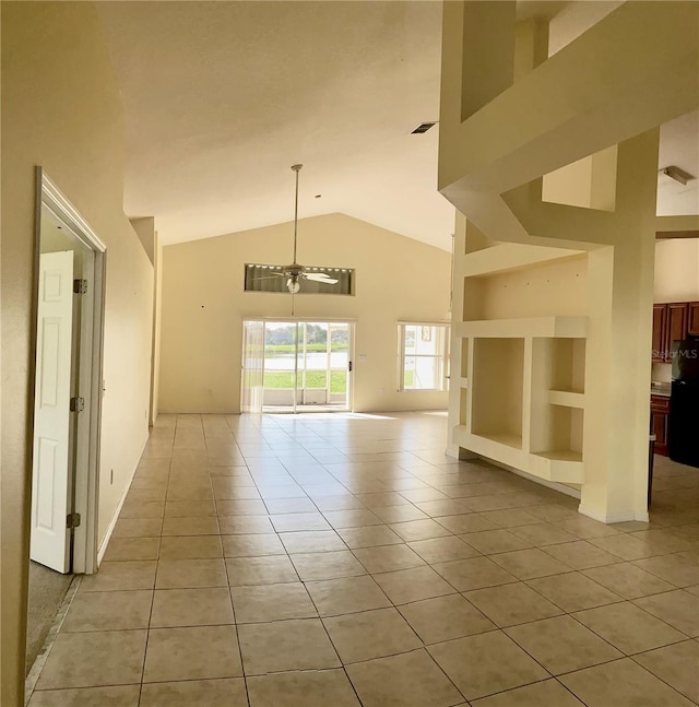 empty room with built in shelves, light tile patterned flooring, and high vaulted ceiling