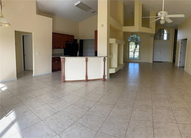 kitchen with high vaulted ceiling, black refrigerator, sink, and light tile patterned floors