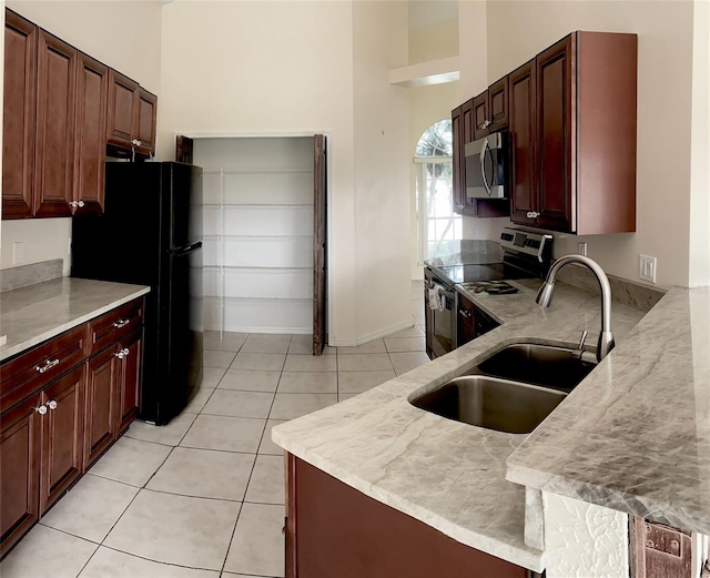 kitchen with a towering ceiling, appliances with stainless steel finishes, sink, and light tile patterned flooring