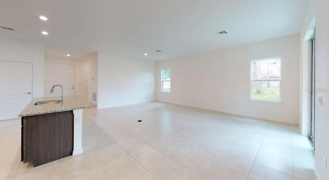 unfurnished living room with light tile patterned flooring and sink