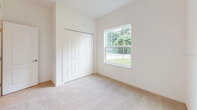 unfurnished bedroom with a closet and light colored carpet