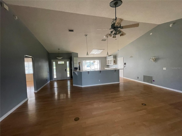 unfurnished living room with high vaulted ceiling, wood-type flooring, and ceiling fan