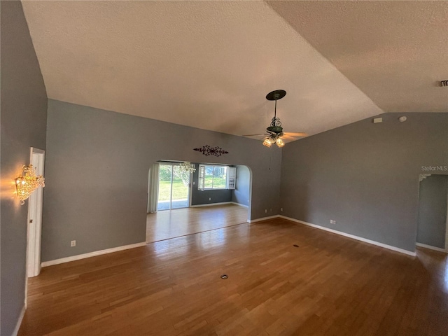 empty room featuring baseboards, ceiling fan, wood finished floors, vaulted ceiling, and a textured ceiling