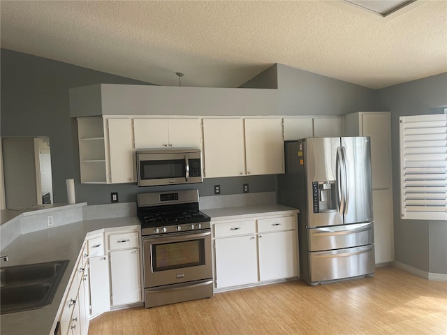 kitchen featuring a sink, white cabinetry, vaulted ceiling, appliances with stainless steel finishes, and open shelves