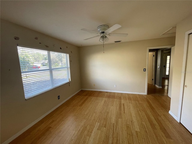 unfurnished room with visible vents, light wood-type flooring, a ceiling fan, and baseboards