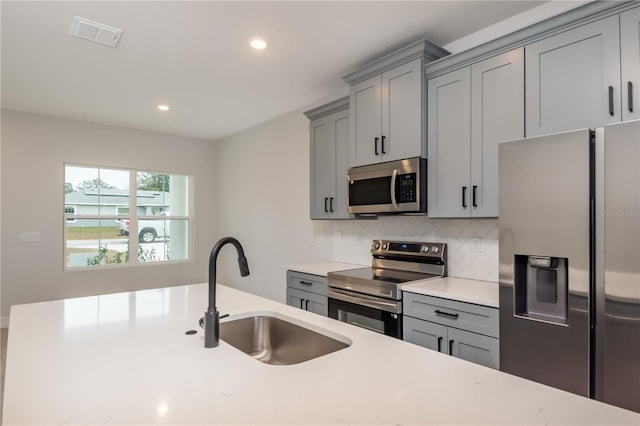 kitchen with tasteful backsplash, gray cabinetry, sink, and stainless steel appliances