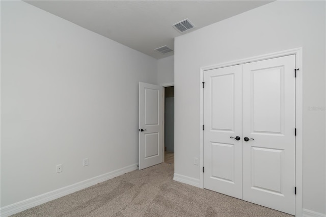 unfurnished bedroom with a closet and light colored carpet