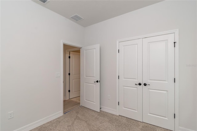 unfurnished bedroom featuring a closet and light colored carpet