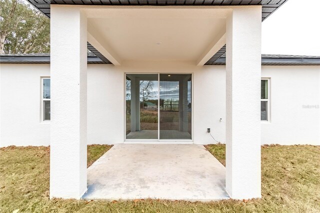 doorway to property featuring a patio and a lawn