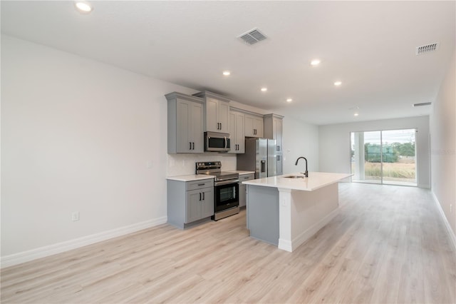 kitchen with gray cabinetry, sink, an island with sink, and stainless steel appliances