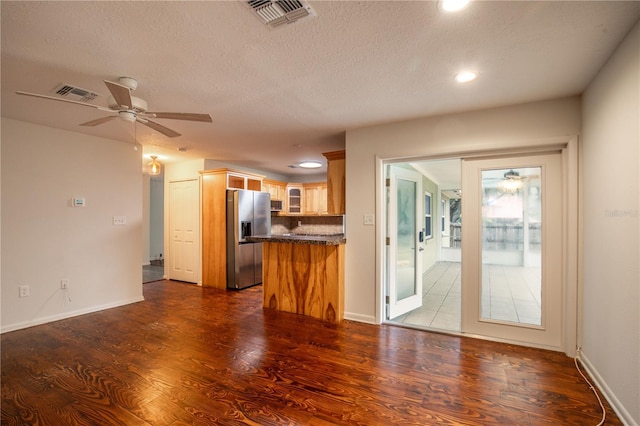 kitchen with kitchen peninsula, stainless steel fridge, ceiling fan, dark hardwood / wood-style flooring, and a textured ceiling