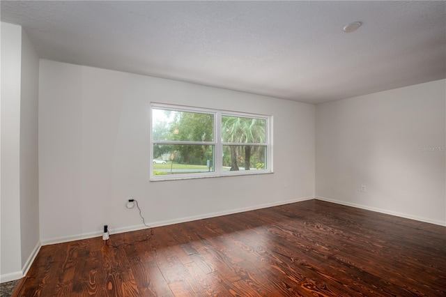 spare room featuring a textured ceiling and dark hardwood / wood-style floors