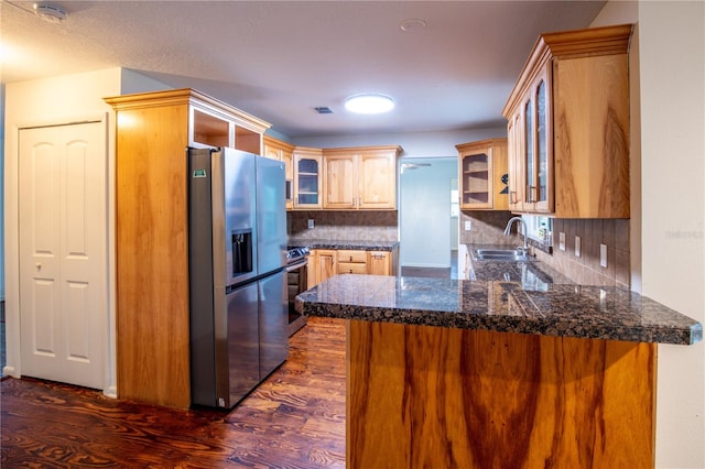 kitchen featuring kitchen peninsula, stainless steel appliances, backsplash, sink, and dark hardwood / wood-style flooring