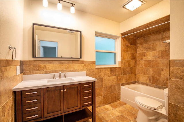 full bathroom featuring toilet, tiled shower / bath, vanity, and tile walls