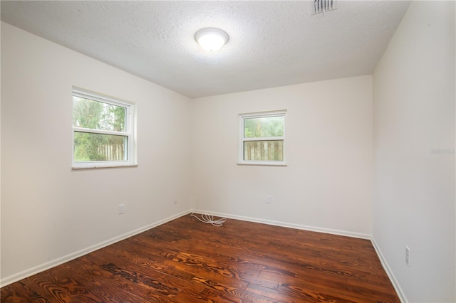 spare room featuring dark hardwood / wood-style floors and a textured ceiling