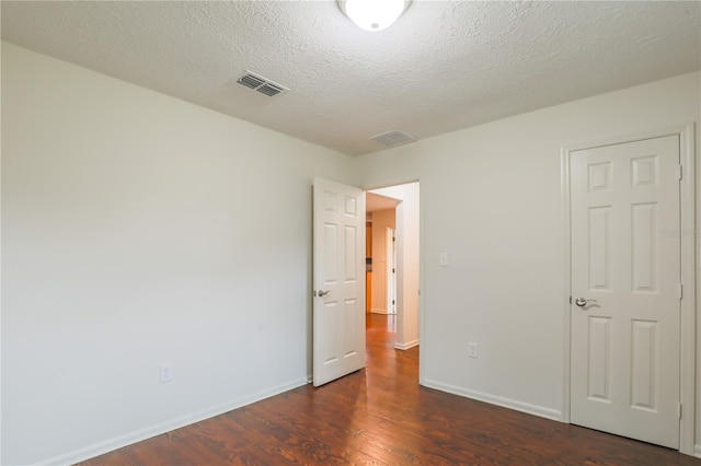 unfurnished bedroom featuring dark wood-type flooring and a textured ceiling