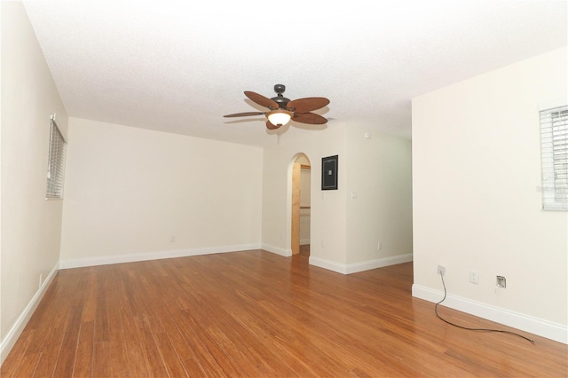 empty room with wood-type flooring, a textured ceiling, electric panel, and ceiling fan