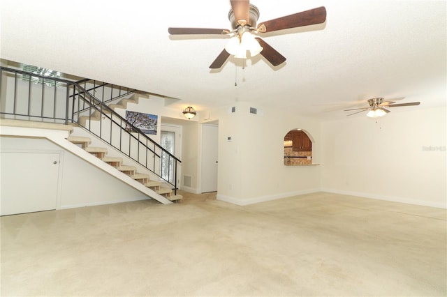 unfurnished living room with ceiling fan, carpet floors, and a textured ceiling