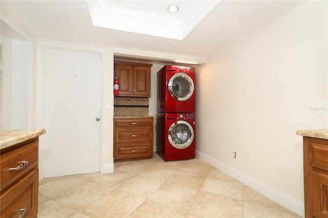 laundry room with cabinets, stacked washer / dryer, and light tile patterned flooring