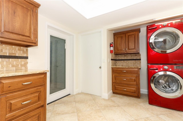 laundry area with cabinets, light tile patterned floors, and stacked washer / dryer