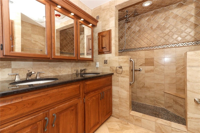 bathroom featuring a tile shower, vanity, tasteful backsplash, and tile walls