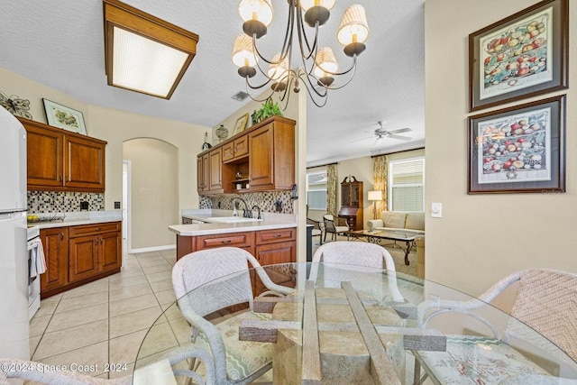 tiled dining room featuring a textured ceiling, sink, and ceiling fan with notable chandelier