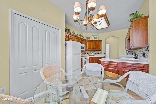 kitchen featuring decorative backsplash, light tile patterned floors, a chandelier, decorative light fixtures, and white appliances