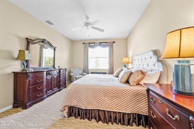 bedroom featuring a textured ceiling, light colored carpet, and ceiling fan