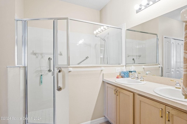 bathroom featuring a shower with door and vanity