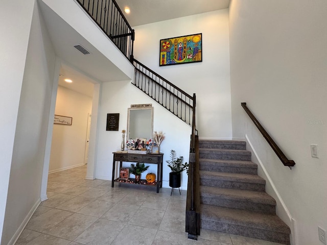 stairs featuring tile patterned floors and a high ceiling