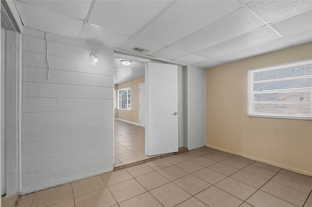 spare room with a paneled ceiling and light tile patterned flooring