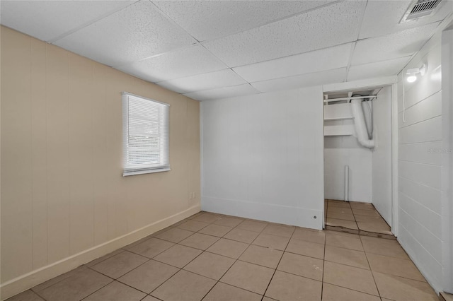 tiled spare room with a drop ceiling