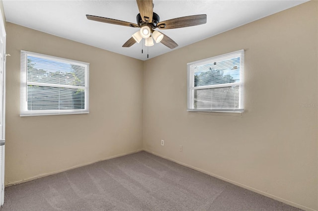 carpeted spare room with ceiling fan and plenty of natural light